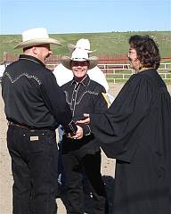 Don and James in black cowboy atire and straw hats with the female preacher in black robe